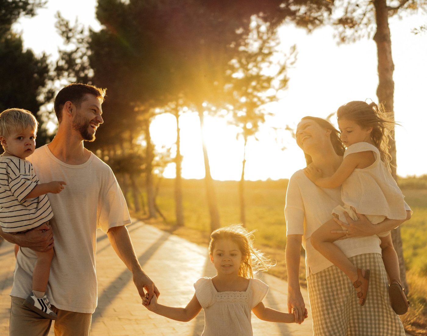 A mom and dad walking down a sunny path with their three little ones